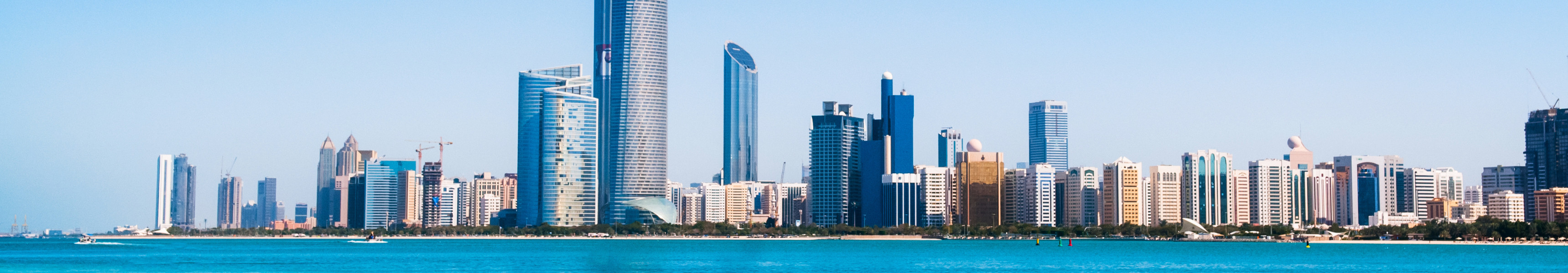 Strand mit türkisblauem Wasser vor der modernen Skyline von Abu Dhabi, Vereinigte Arabische Emirate