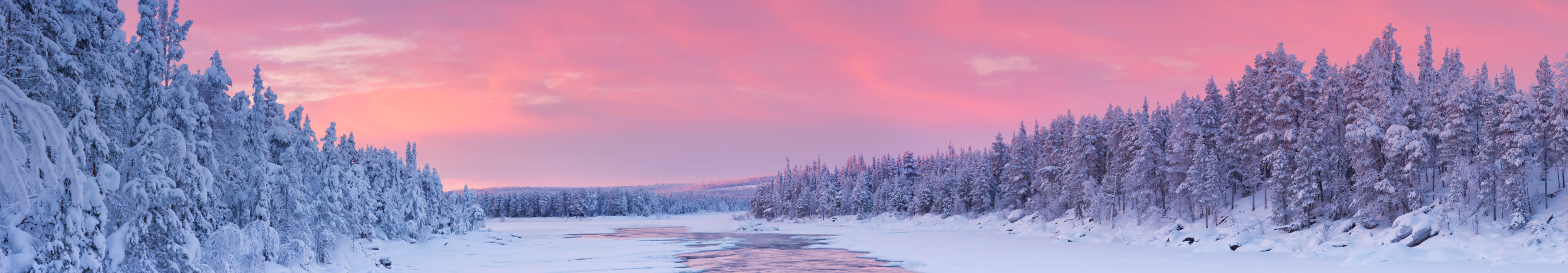 Sonnenaufgang über einem Fluss in einer Winterlandschaft, Finnisch-Lappland