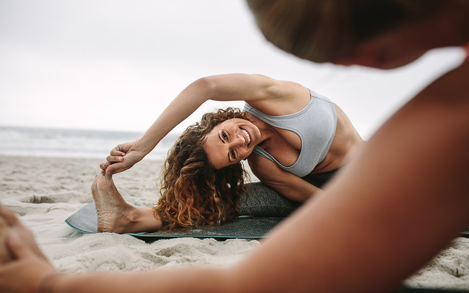 Frau macht Yoga am Strand