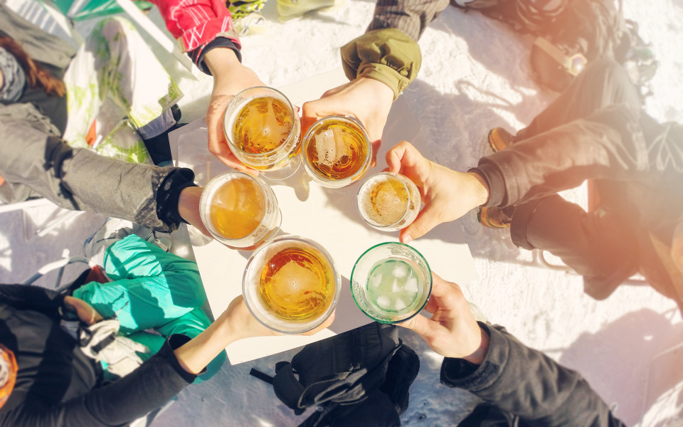 Gruppe von Freunden, die in der Pause beim Skifahren Bier trinken