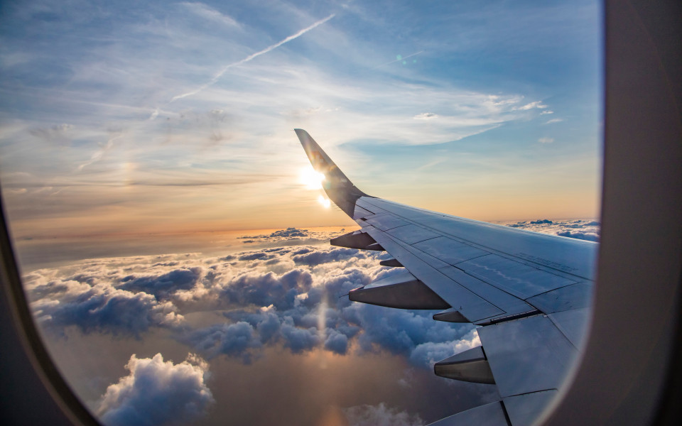 Blick von einem Fensterplatz aus auf das Flugzeug mit Wolken und Sonnenuntergang 