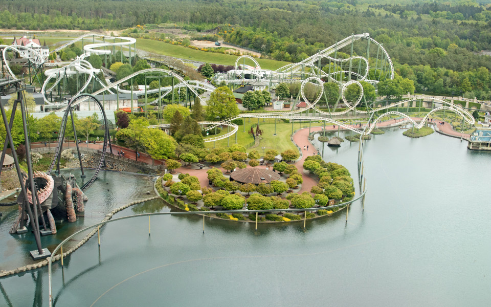 Achterbahn im Heide Park Soltau mit steilen Abfahrten, mehreren Loopings und einer kurvigen Strecke, umgeben von gr&uuml;nen Landschaften.